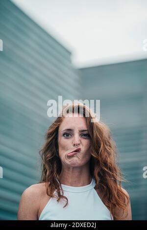 Jeune femme se faisant le visage en se tenant debout à l'extérieur Banque D'Images