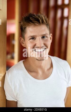 Jeune homme souriant debout à la maison Banque D'Images