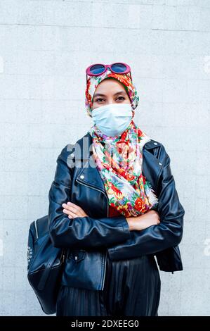 Femme musulmane confiante debout avec les bras croisés contre le mur pendant COVID-19 Banque D'Images