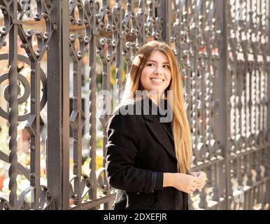 Jeune femme souriant debout contre la porte Banque D'Images