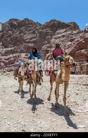 Des Bédouins qui portent des chameaux colorés à travers l'ancien site de Pétra en Jordanie. Ils prennent des touristes pour des promenades à travers les ruines de Petra. Banque D'Images