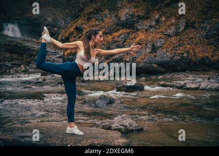 Equilibrage des athlètes en faisant du yoga en rivière dans la forêt au parc national d'Ordesa, Huesca, Espagne Banque D'Images