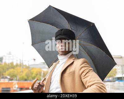Jeune homme tenant un parapluie à l'extérieur Banque D'Images