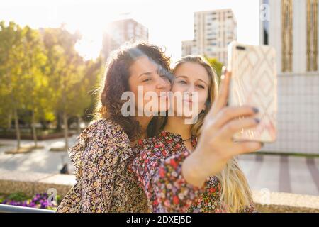 Des amies qui se font du pucking tout en emportant leur selfie sur leur smartphone jour ensoleillé Banque D'Images