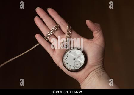 Main de femme tenant une montre de poche antique Banque D'Images