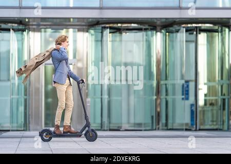 Homme d'affaires insouciant à bord d'un scooter électrique sur une piste de marche Banque D'Images