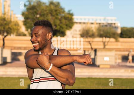 Homme souriant qui étire les bras tout en se tenant au stationnement Banque D'Images