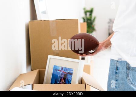 Homme tenant le ballon de rugby à la main tout en le déballant à nouveau appartement Banque D'Images