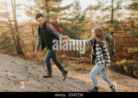 Jeune couple tenant les mains tout en marchant en haut de la colline pendant l'automne randonnée Banque D'Images