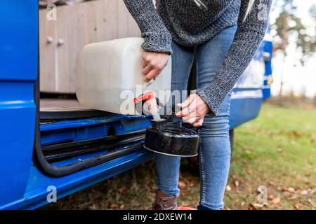 Femme de taille moyenne qui verse de l'eau dans une théière de camping Banque D'Images