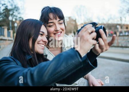 Femme souriante debout par une amie qui prend une photo avec un reflex numérique appareil photo Banque D'Images