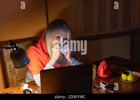 Femme âgée qui pleure en regardant les appels vidéo sur ordinateur portable assis à la maison Banque D'Images
