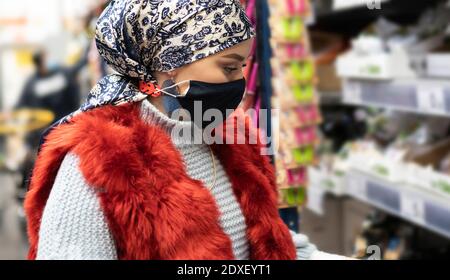 Jeune femme portant un foulard et masque de protection shopping pendant au supermarché Banque D'Images