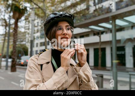 Femme portant un casque de vélo tout en étant debout dans la rue en ville Banque D'Images