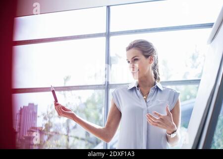 Une jeune femme d'affaires confiante explique sur un tableau de conférence pendant la réunion au bureau Banque D'Images