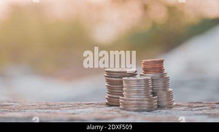 les pièces de monnaie s'empilent sur un fond de lumière solaire de table en bois Banque D'Images