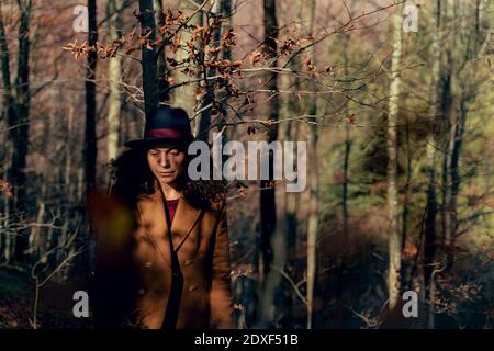 Triste femme regardant vers le bas en se tenant dans la forêt Banque D'Images