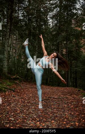 Femme aux bras étirés pratiquant la gymnastique rythmique en forêt Banque D'Images