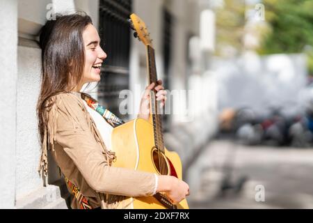 Une musicienne riant en jouant de la guitare en ville Banque D'Images