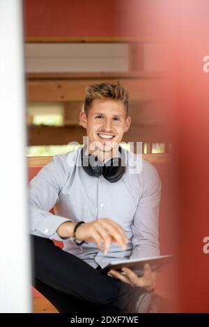 Jeune homme souriant en utilisant une tablette numérique à la maison Banque D'Images