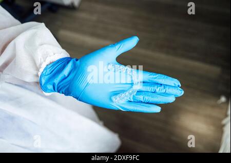 Dentiste portant des vêtements de travail de protection tenant un renfort transparent en se tenant debout clinique Banque D'Images