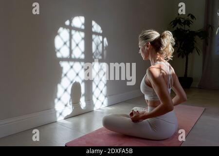 Femme mature pratiquant la position de lotus dans la salle d'exercice à la maison Banque D'Images