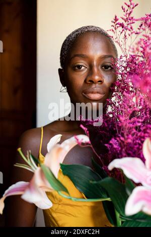 Femme adulte de taille moyenne tenant des fleurs à la maison Banque D'Images