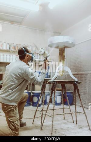 Table de peinture pour ouvrier manuel masculin avec pistolet à peinture à l'atelier Banque D'Images