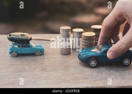 Main tenant les pièces de monnaie modèle de voiture pile sur la table en bois Finance Concept d'assurance et de transport Banque D'Images