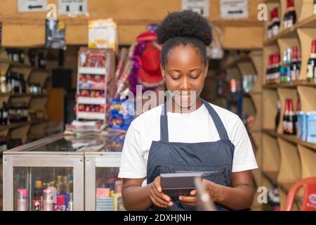 une femme africaine souriant tout en utilisant une calculatrice Banque D'Images