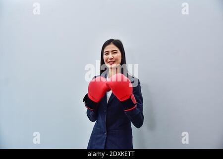 Femmes d'affaires employée de bureau portant des gants de boxe debout sur fond blanc Banque D'Images