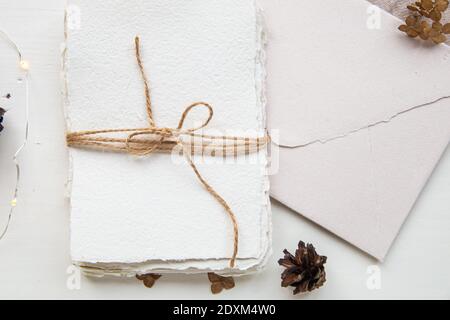 Pose plate style hygge. Liste de souhaits de Noël. Papier fait à la main noué avec des fils artisanaux. Enveloppe de lettre, cônes de pin, fil de métier. Banque D'Images