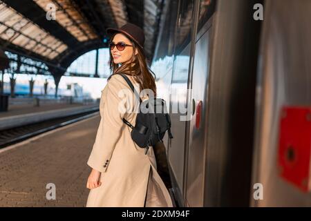 Beau voyageur avec sac à dos sur la plate-forme de la gare. Jeune femme près du train Banque D'Images