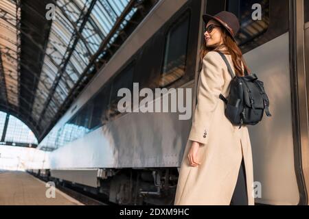 Beau voyageur avec sac à dos sur la plate-forme de la gare. Jeune femme près du train Banque D'Images