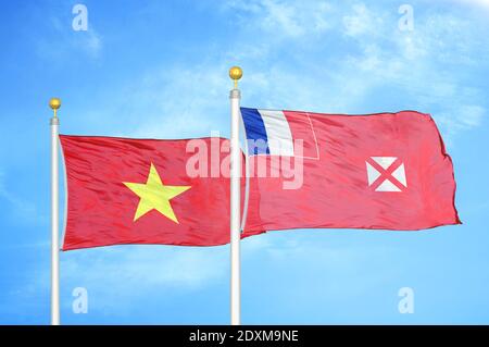 Vietnam et Wallis et Futuna deux drapeaux sur les mâts de drapeaux et ciel bleu Banque D'Images