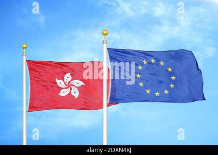 Hong Kong et l'Union européenne deux drapeaux sur les mâts de drapeaux et ciel bleu nuageux Banque D'Images