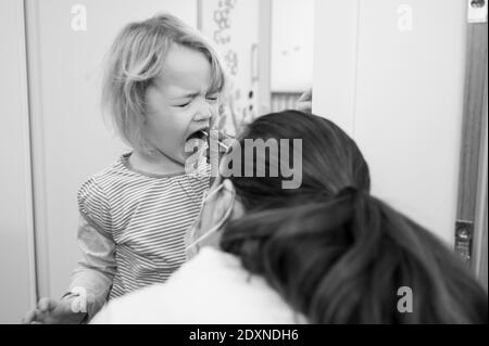 Fille blonde ayant un écouvillon oropharyngé inséré pour la détection de covid 19. Banque D'Images