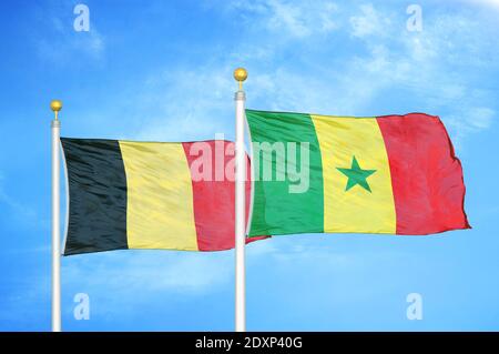 La Belgique et le Sénégal deux drapeaux sur les mâts et le bleu nuageux ciel Banque D'Images