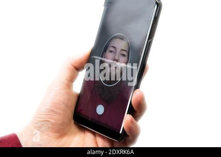 Jeune homme tenant un téléphone mobile pour scanner le visage, pour changer le visage à une autre technologie de visage et faux, concept isolé sur fond blanc Banque D'Images