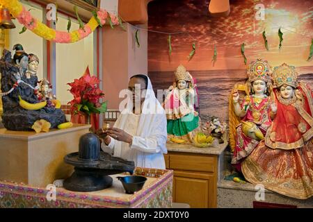 Un adorateur hindou dévot prie et médite devant un Shiva lingam. À l'intérieur d'un temple à South Richmond Hill, Queens, New York. Banque D'Images