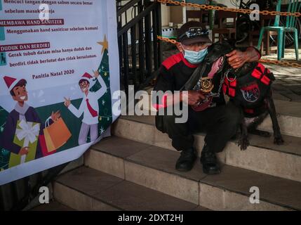 24 décembre 2020, Malang, East Java, Indonésie : un membre de la police indonésienne K-9 plaisantait avec un chien sniffer lorsqu'il se sécurise avant le service de Noël en dehors de la page d'une église dans la ville indonésienne à majorité musulmane, Malang, East Java, Indonésie, le 24 décembre, 2020.la police indonésienne mène des mesures de protection plus strictes en place l'agitation et les lieux de culte aux actes de terreur pendant les fêtes de Noël et le nouvel an 2020/2021. Après 23 terroristes présumés ont été arrêtés et des matériaux de fabrication de bombes à Lampung, Sumatra, qui étaient membres du groupe terroriste Jemaah Islamiyah (JI), sur Decemb Banque D'Images