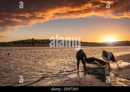 Appledore, North Devon, Angleterre. Jeudi 24 décembre 2020. Météo Royaume-Uni. Après une nuit de pluie torrentielle et de vent de force, au lever du soleil, deux amis mettent leur bateau à la balle tandis que les nuages de tempête se brisent sur la côte du Devon du Nord, sur l'estuaire de la rivière Torridge, au petit village côtier d'Appledore. Crédit : Terry Mathews/Alay Live News Banque D'Images