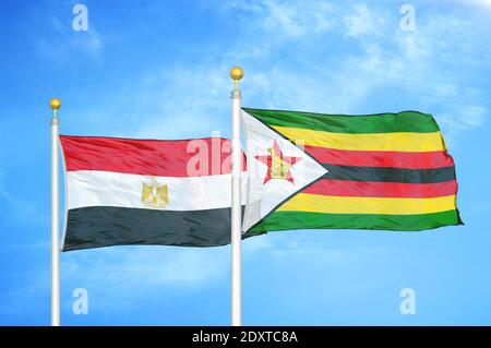 Égypte et Zimbabwe deux drapeaux sur les mâts de drapeaux et bleu nuageux ciel Banque D'Images