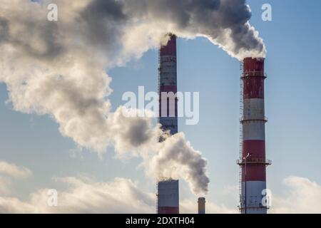 Fumée épaisse provenant de trois cheminées d'usine. Tuyaux d'usine avec fumée sur fond bleu ciel. Réchauffement de la planète. Pollution de l'air. Espace de copie, horizontal Banque D'Images