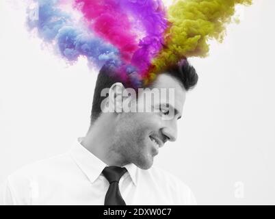 Fumée colorée provenant de la tête de l'homme souriant contre fond blanc