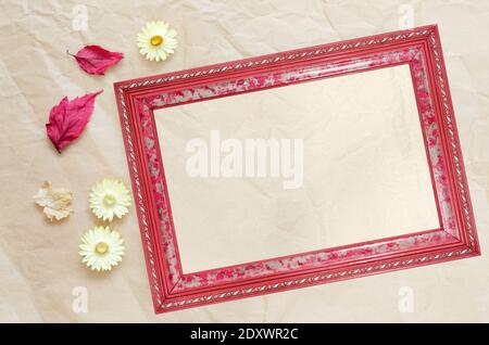 Cadre photo avec papier propre pour le texte, les feuilles séchées et les fleurs sur un fond de papier beige froissé, vue du dessus Banque D'Images