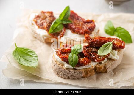 Bruschetta aux tomates séchées, fromage cottage et basilic frais. Savoureux hors-d'œuvre italiens Banque D'Images