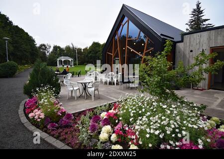 Café Laut dans le jardin botanique d'Akureyri, nord de l'Islande. Des parterres de fleurs entourent le patio rempli de chaises et de tables devant le bâtiment moderne. Banque D'Images