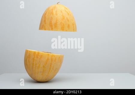 vol de deux moitiés de melon sur la table, lévitation de fruits frais mûrs juteux, nourriture naturelle saine végétarienne biologique, lieu pour le texte Banque D'Images