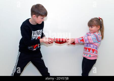 2 enfants caucasiens tirant un Cracker de Noël. Banque D'Images